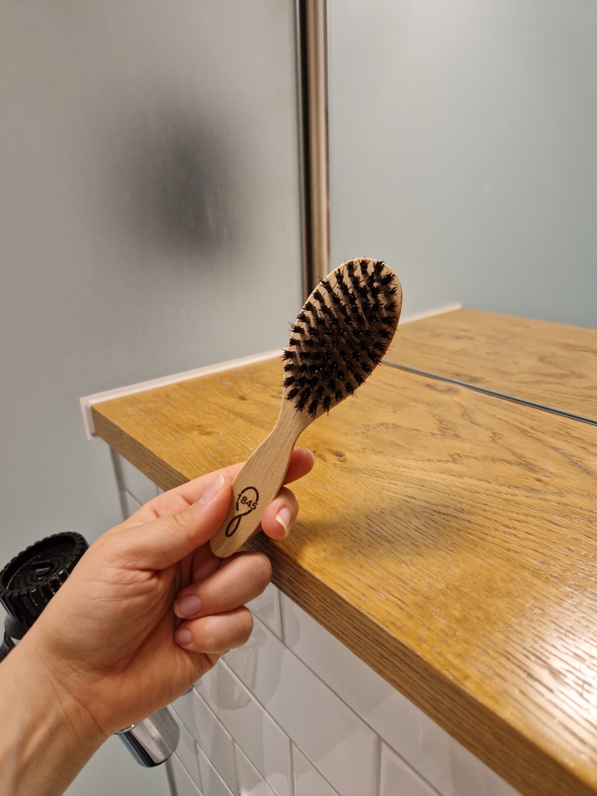 Brosse à barbe 1845 en bois de hêtre et soies de sanglier tenue au-dessus d'un plan de salle de bains Brosse à barbe 1845 en bois de hêtre et soies de sanglier tenue au-dessus d'un plan de salle de bains